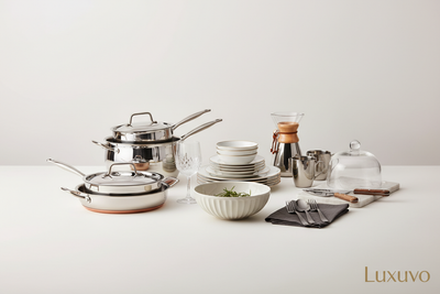 Generate a premium Shopify collection banner for Kitchen & Dining. Display luxury kitchenware, cookware, tableware, and dining accessories on a clean white or light beige background. Use soft, professional lighting, subtle shadows, and a sophisticated catalog-style layout. Include the brand name ‘Luxuvo’ subtly in the corner in an elegant font. Make it full-width, responsive, high-resolution, suitable for a luxury online store.